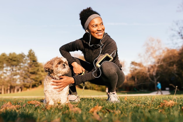 Fröhliche schwarze Sportlerin und ihr Hund genießen einen Tag in der Natur
