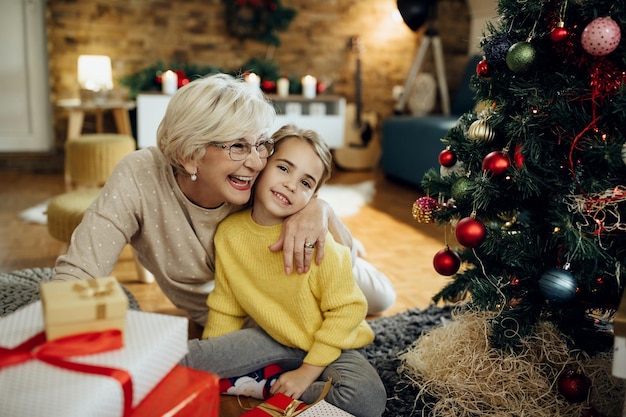 Fröhliche Seniorin und ihre Enkelin genießen Weihnachten zu Hause