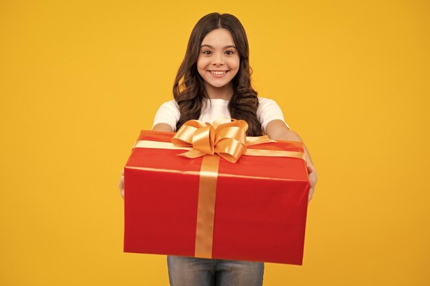 Fröhliche Teenager positive und lächelnde Emotionen von Teenager-Mädchen Kind mit Geschenkbox auf isoliertem Studiohintergrund Gifting für Kindergeburtstag