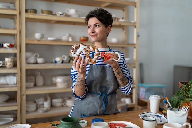 Fröhliche Töpfermeisterin, die im Keramikstudio eine Kaffeepause macht und im Tonstudio zu Mittag isst