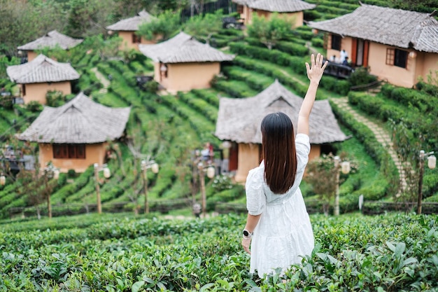 Fröhliche Touristenfrau im weißen Kleid genießt einen schönen TeegartenReisende besuchen das thailändische Dorf Ban Rak Mae Hong Son Thailand Reiseurlaub und Urlaubskonzept