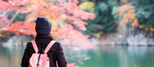 Fröhliche Touristin, die bunte Blätter und den Katsura-Fluss in Arashiyama sucht. Junge asiatische Reisende besuchen Kyoto und genießen Reisen in Japan