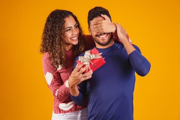 Fröhliche und aufgeregte junge Paare, die ihre Augen bedeckten, überraschten mit einem Geschenk.