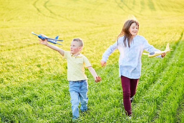 Fröhliche und glückliche Kinder spielen auf dem Feld und stellen sich vor, an einem sonnigen Sommertag Piloten zu sein. Kinder träumen vom Fliegen und Fliegen