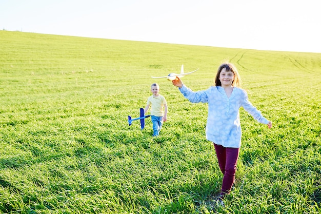 Fröhliche und glückliche Kinder spielen auf dem Feld und stellen sich vor, an einem sonnigen Sommertag Piloten zu sein. Kinder träumen vom Fliegen und Fliegen