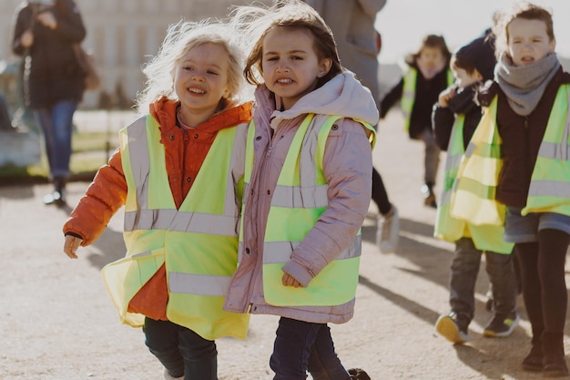 Fröhliche und lächelnde Kinder verschiedener Nationalitäten gehen mit Tutoren