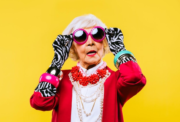 Fröhliche und lustige coole alte Dame mit modischer Kleidung Porträt auf farbigem Hintergrund Junge Großmutter mit extravaganten Stilkonzepten über Lifestyle-Alter und ältere Menschen