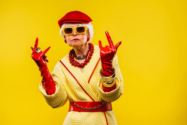 Foto fröhliche und lustige coole alte dame mit modischer kleidung porträt auf farbigem hintergrund junge großmutter mit extravaganten stilkonzepten über lifestyle-alter und ältere menschen