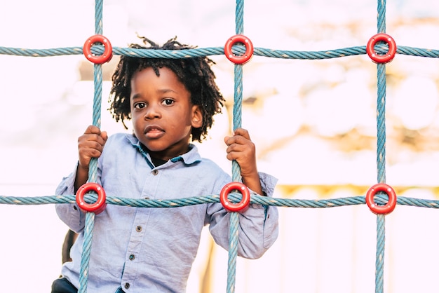 Fröhliche und schöne junge schwarze Rasse Afrikaner mit ethnischen alternativen Haaren, die auf einem Spielplatz mit farbigen Schnüren spielen und Spaß haben