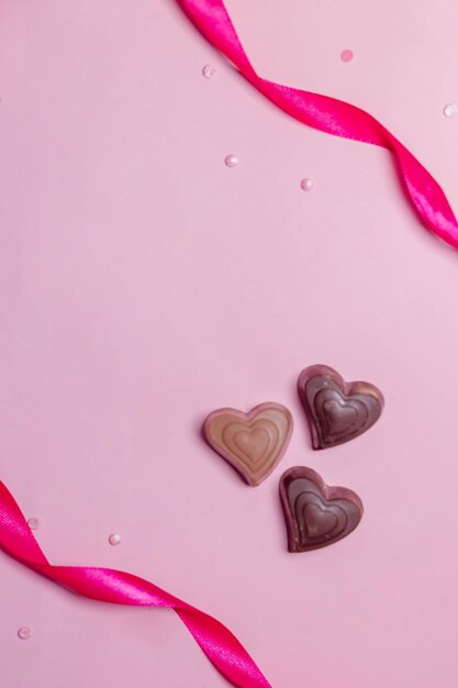 Fröhliche Valentinstagskarte mit roten Konfetti-Bonbons in Herzform auf rosa Hintergrund