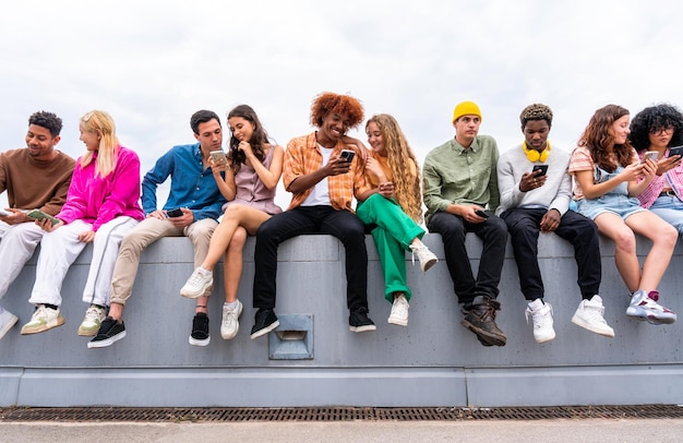 Foto fröhliche, verspielte multiethnische gruppe junger freunde, die sich im freien treffen