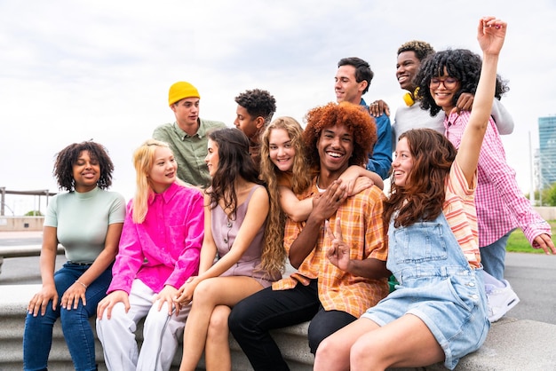 Foto fröhliche, verspielte multiethnische gruppe junger freunde, die sich im freien treffen