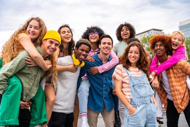 Fröhliche, verspielte multiethnische Gruppe junger Freunde, die sich im Freien treffen