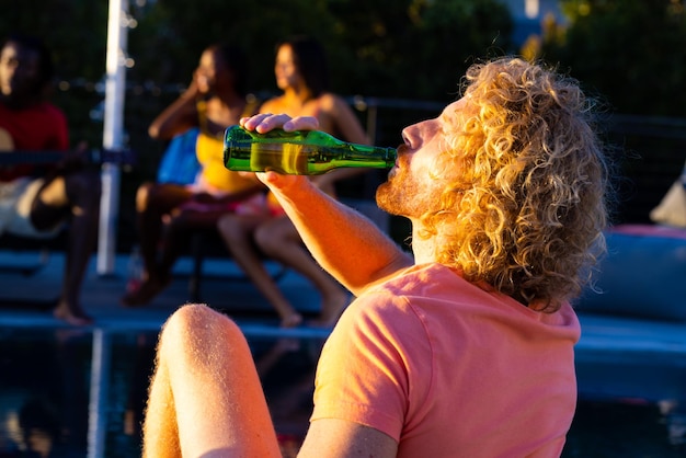 Fröhliche, vielfältige Gruppe von Freunden, die eine Poolparty feiern und Bier im Garten trinken. Lebensstil, Freundschaft und Party, Sommer, Sonnenschein, unverändert.