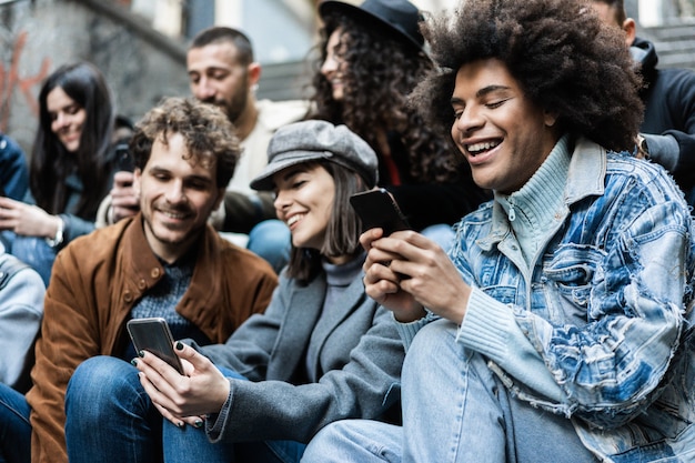 Fröhliche, vielfältige Menschen, die Mobiltelefone im Freien in der Stadt benutzen - Konzentrieren Sie sich auf das Gesicht des afrikanischen Mannes