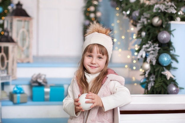 Fröhliche Weihnachten! Oberfläche. kleines Mädchen in einem Hut mit Schnee in den Händen nahe Briefkasten im Winteryard. Mädchen schickte einen Brief an den Weihnachtsmann mit einer Liste von Weihnachtsgeschenken. Kind sendet eine Nachricht an den Nordpol.