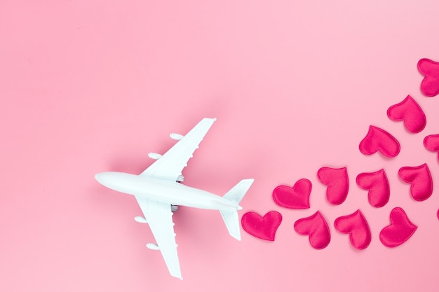 Fröhlichen Valentinstag. Spielzeugflugzeug und rote Herzen, auf einem rosa Hintergrund