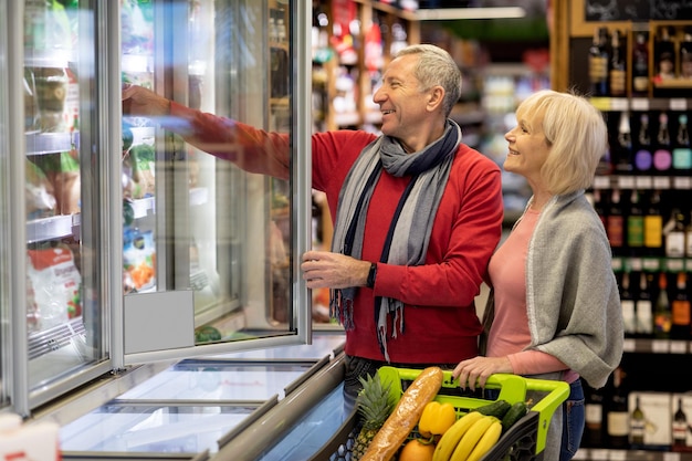 Fröhlicher älterer Ehemann und Ehefrau, die Waren im Supermarkt auswählen