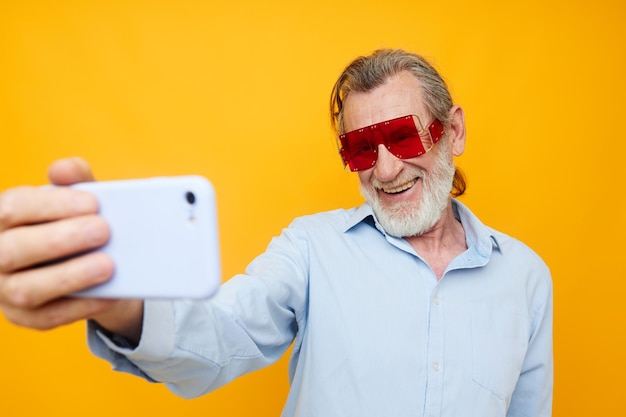 Fröhlicher älterer Mann in modischer Brille mit telefongelbem Hintergrund