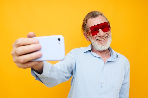 Fröhlicher älterer Mann in modischer Brille mit telefongelbem Hintergrund