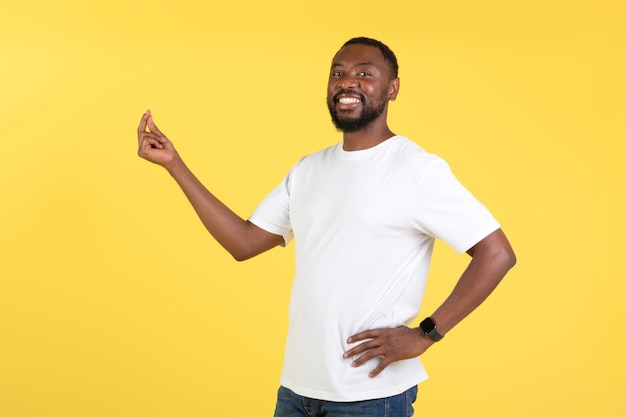 Fröhlicher Afroamerikaner, der mit den Fingern klickt, die über gelbem Hintergrund stehen