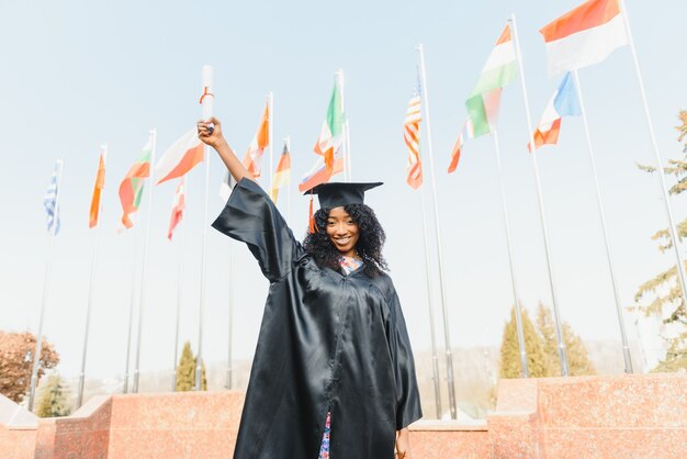 Fröhlicher afroamerikanischer Doktorand mit Diplom in der Hand