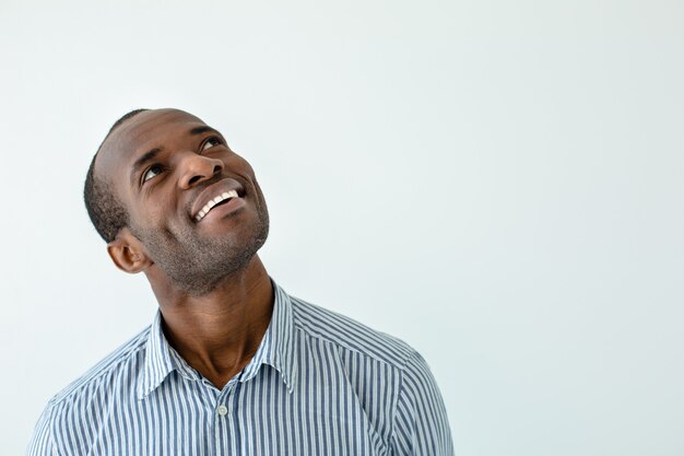 Fröhlicher afroamerikanischer Mann, der beim Aufblicken lächelt
