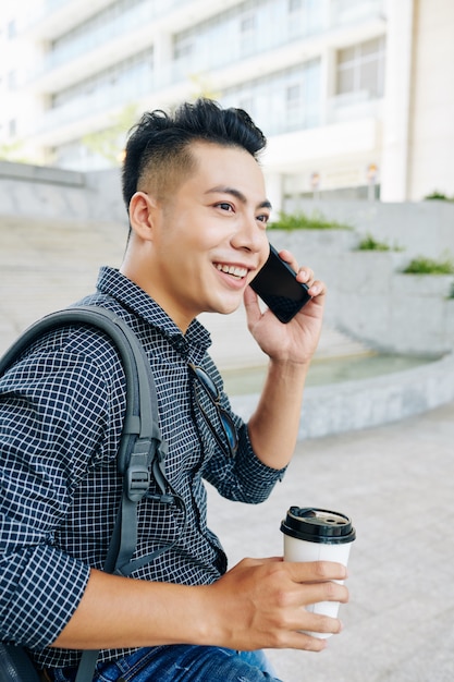 Fröhlicher asiatischer Mann, der am Telefon spricht