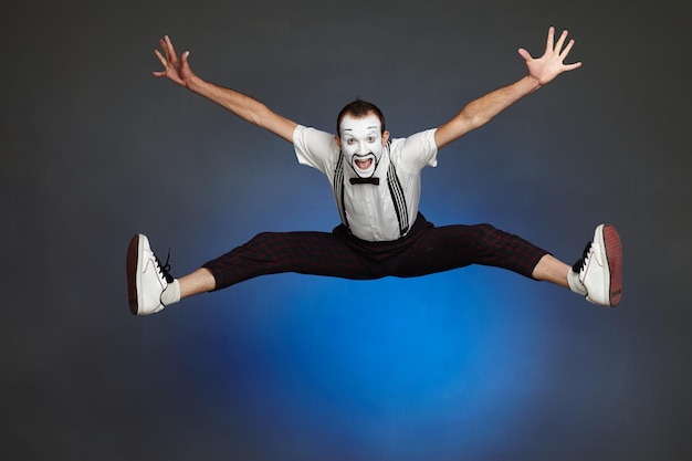 Foto fröhlicher clown mime springt weit und spreizt arme und beine