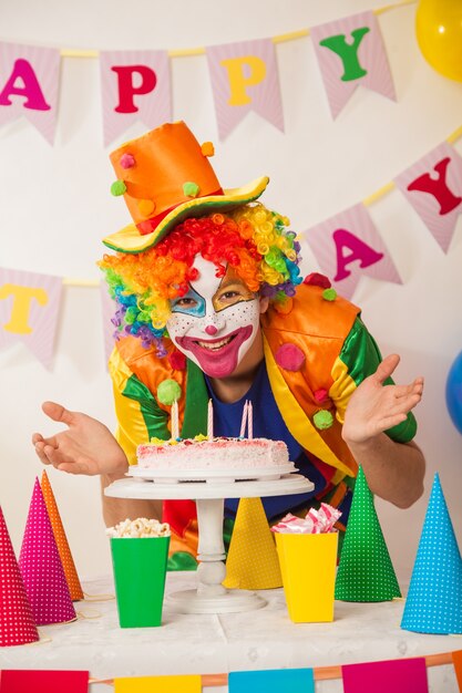 Fröhlicher Clownjunge im Urlaub mit einem Kuchen