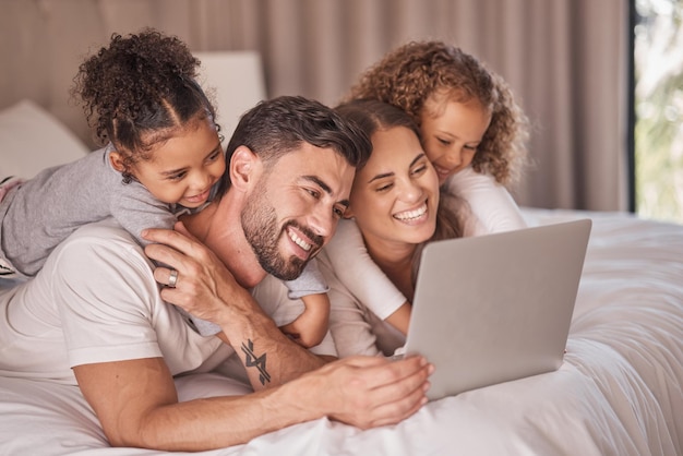 Fröhlicher Familien-Laptop und Kinder, die zusammen mit ihrer Mutter und ihrem Vater ein Live-Stream-Cartoon-Abonnement im Bett genießen