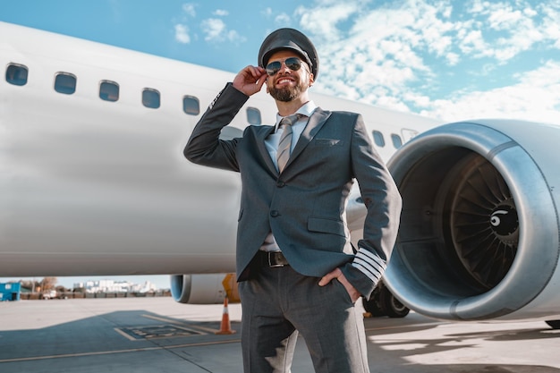 Foto fröhlicher flugzeugpilot, der draußen am flugplatz steht