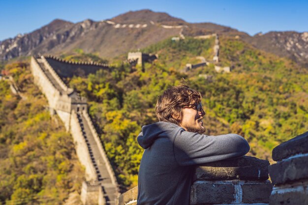 Fröhlicher, fröhlicher Touristenmann an der Chinesischen Mauer, der Spaß auf Reisen hat, lächelt, lacht und