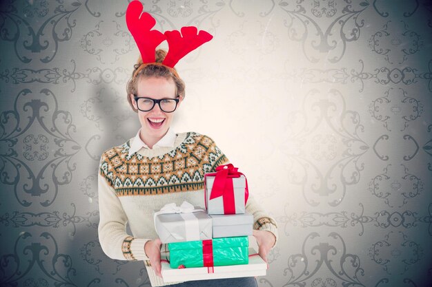 Foto fröhlicher geekiger hipster mit geschenken vor elegant gemusterter tapete in grautönen