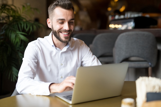 Fröhlicher Geschäftsmann, der im Café arbeitet