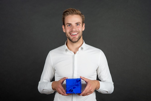 Fröhlicher Geschäftsmann hält Geschenkbox für den Tag der Männer oder Frauen