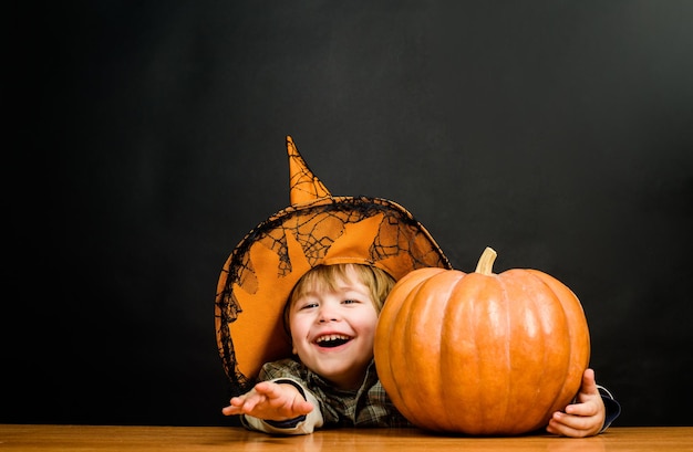 Fröhlicher Halloween-lustiger Kinderjunge im Hexenhut für Halloween mit Kürbis-Jack-Kleinkindkind mit