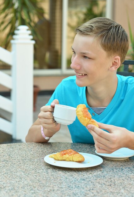 Fröhlicher Junge beim Frühstück auf dem Tisch