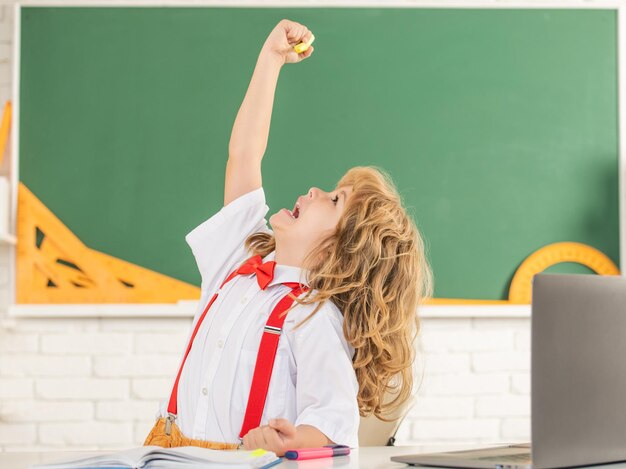 Fröhlicher Junge im Fliegestudium in der Schulklasse an der Tafelschule