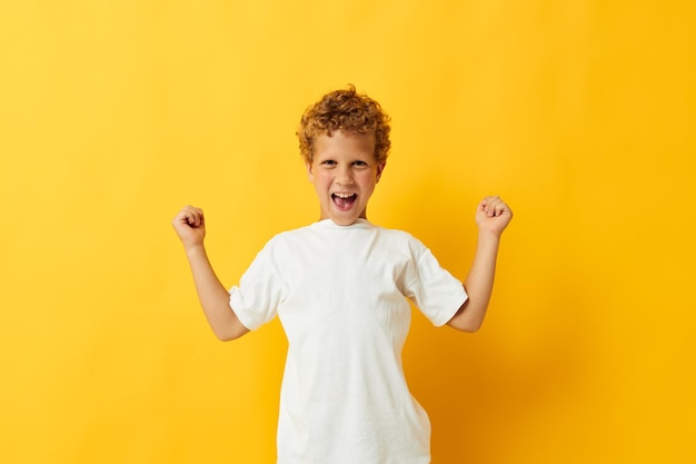 Fröhlicher Junge in einem weißen T-Shirt mit gelber Hintergrund-Kindheit