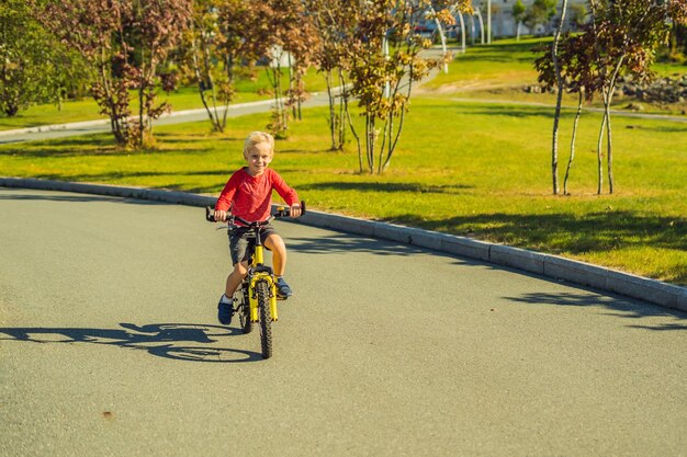 Fröhlicher Junge von 5 Jahren, der sich an einem schönen Tag mit dem Fahrrad im Park amüsiert