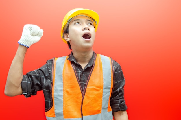 Fröhlicher junger asiatischer männlicher Bauarbeiter, Ingenieur, Baumeister, der seine Fäuste erhebt und eine Ja-Geste macht