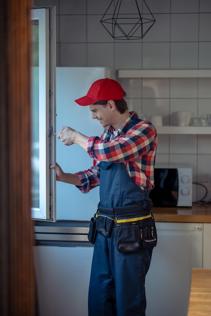 Fröhlicher junger Mann, der ein Küchenfenster montiert