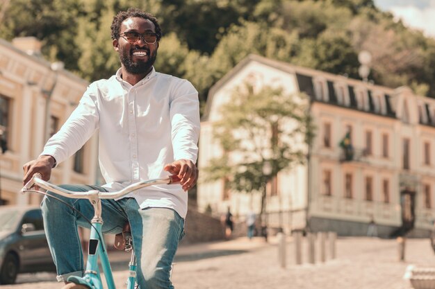 Fröhlicher junger Mann, der es genießt, mit seinem Fahrrad die Straße hinunter zu fahren. Vorlagenbanner