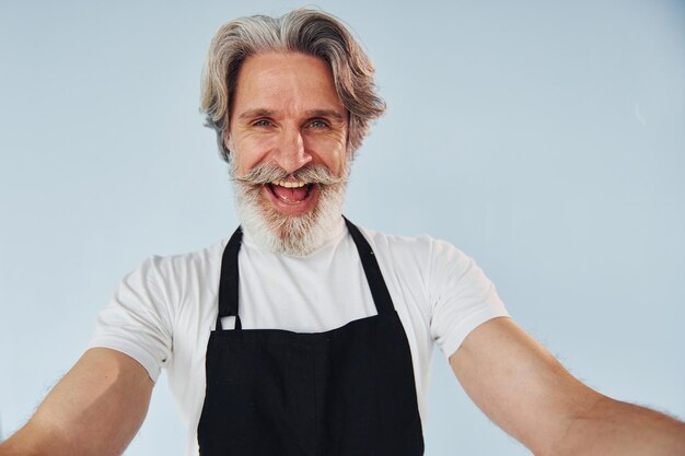 Fröhlicher Kellner macht Selfie Älterer stilvoller moderner Mann mit grauem Haar und Bart drinnen