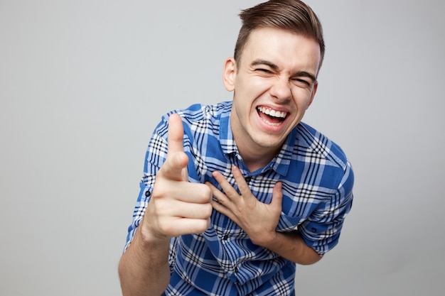 Fröhlicher Kerl in einem karierten Hemd lacht auf weißem Hintergrund im Studio.