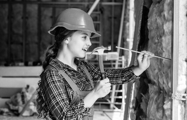 Fröhlicher Kinderingenieur mit Hammerwerkzeug in der Schutzhelmtechnik