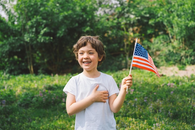 Fröhlicher kleiner patriotischer Junge mit amerikanischer Flagge USA feiern den 4. Juli Glücklicher Unabhängigkeitstag