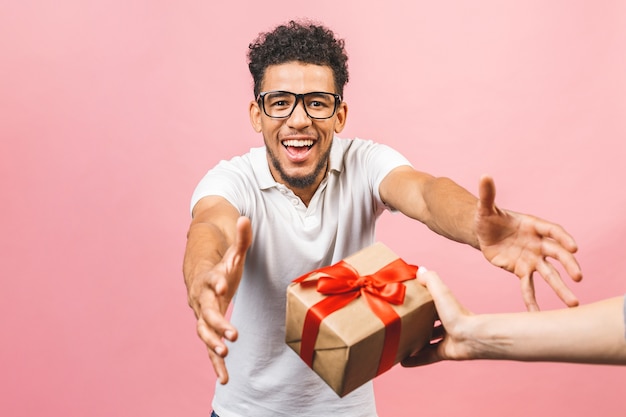 Fröhlicher lächelnder Afroamerikaner in der Brille, die verpackte Geschenkbox hält