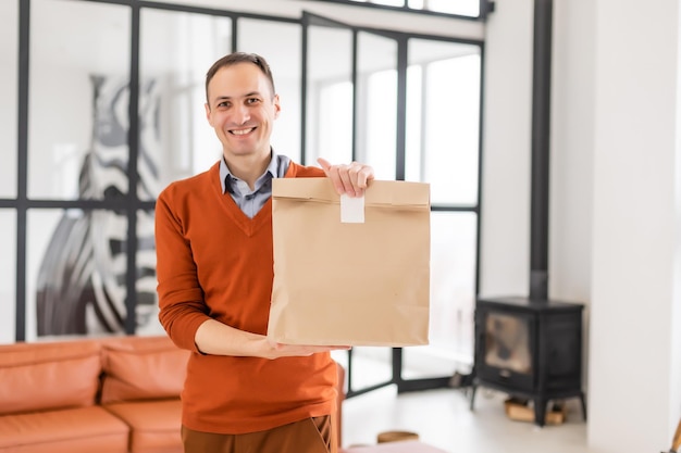 Fröhlicher Lieferbote. Glücklicher junger Kurier, der ein Lieferpaket hält.